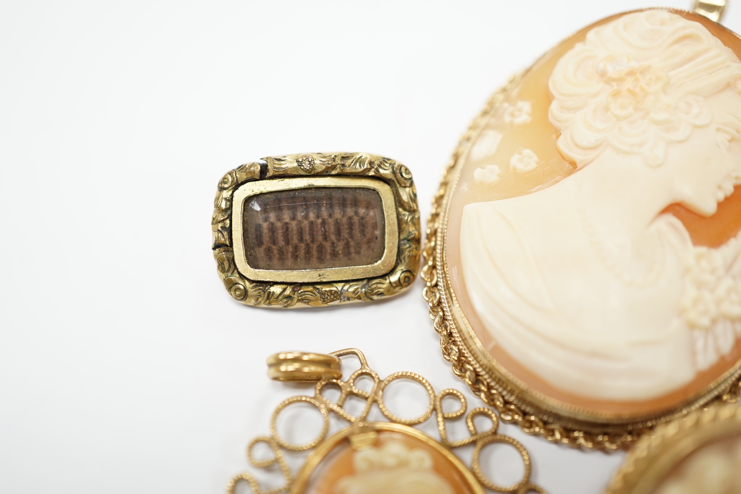 Two modern 9ct gold mounted oval cameo shell pendant brooches, largest 42cm and two other mounted oval cameo shell pendant or brooches and a mourning brooch (a,f,).